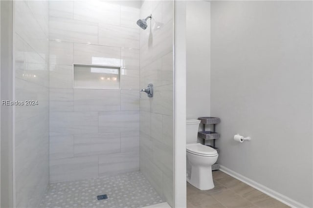 bathroom featuring tiled shower and toilet