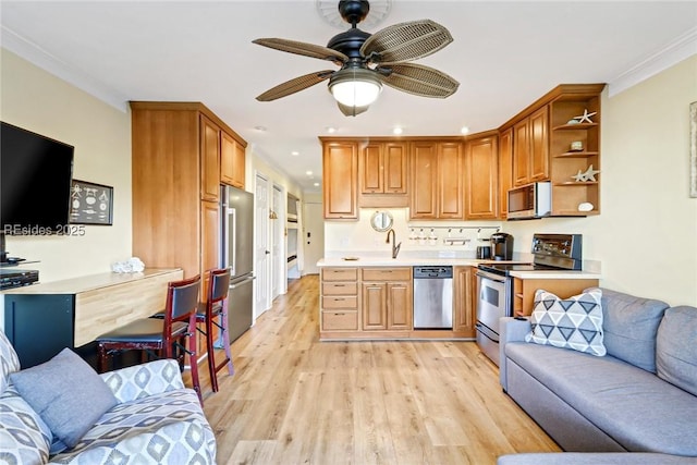 kitchen with appliances with stainless steel finishes, sink, ornamental molding, ceiling fan, and light wood-type flooring