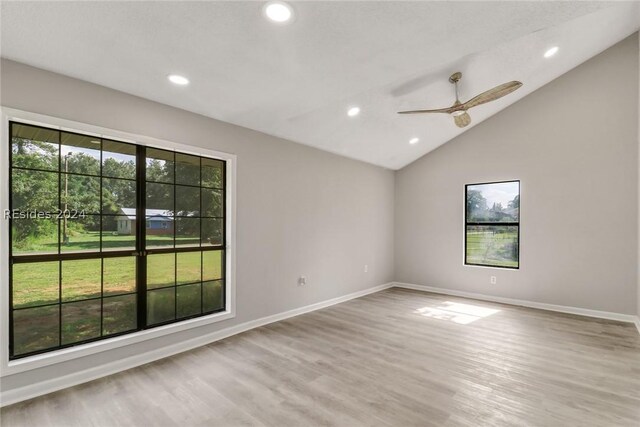 spare room featuring lofted ceiling, a wealth of natural light, ceiling fan, and light hardwood / wood-style flooring