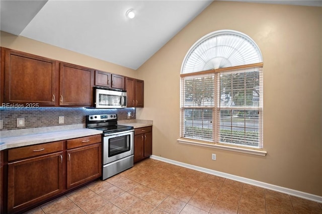 kitchen featuring lofted ceiling, light tile patterned floors, decorative backsplash, and stainless steel appliances