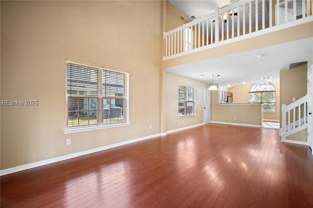 unfurnished living room with a towering ceiling and wood-type flooring