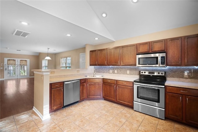 kitchen with pendant lighting, light tile patterned floors, lofted ceiling, stainless steel appliances, and kitchen peninsula