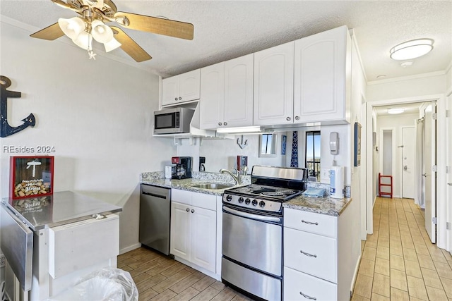 kitchen featuring appliances with stainless steel finishes, sink, white cabinets, and a textured ceiling