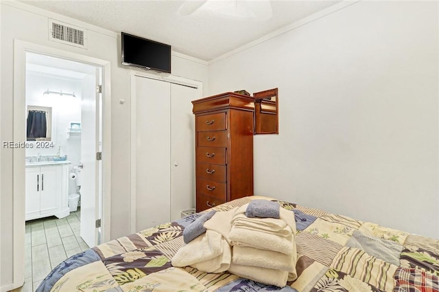 bedroom with ensuite bathroom, sink, ornamental molding, ceiling fan, and a closet