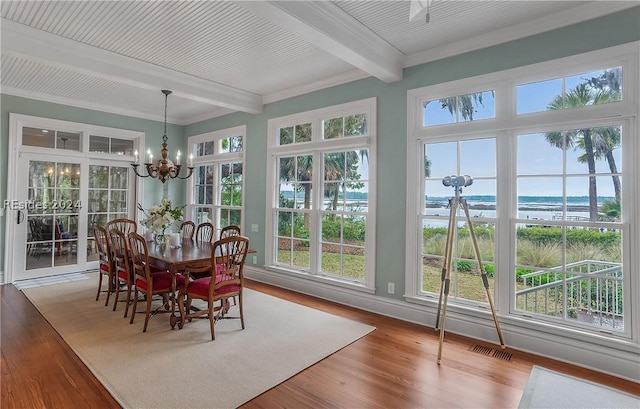 sunroom / solarium featuring a water view, beam ceiling, and a notable chandelier