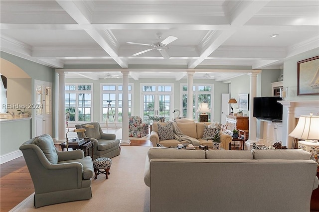 living room featuring hardwood / wood-style floors, crown molding, beamed ceiling, and ornate columns