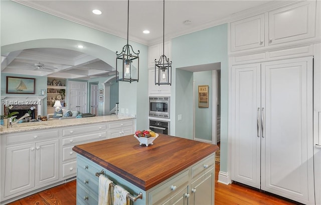 kitchen featuring beam ceiling, built in appliances, coffered ceiling, white cabinets, and a kitchen island