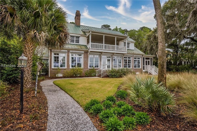 back of property featuring a balcony and a lawn