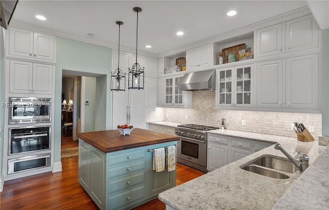 kitchen with white cabinetry, appliances with stainless steel finishes, wooden counters, and wall chimney exhaust hood