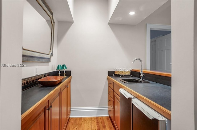 kitchen with stainless steel dishwasher, sink, and light wood-type flooring