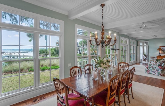 dining room with beamed ceiling, a healthy amount of sunlight, a water view, and hardwood / wood-style flooring