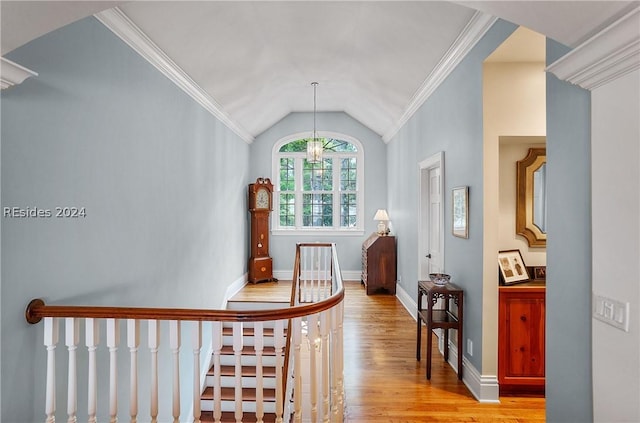 corridor with ornamental molding, lofted ceiling, a chandelier, and light hardwood / wood-style floors