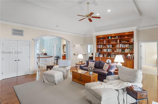 living room featuring ceiling fan, wood-type flooring, ornamental molding, built in shelves, and vaulted ceiling