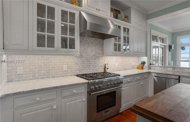 kitchen with white cabinets, stainless steel appliances, decorative backsplash, and wall chimney range hood