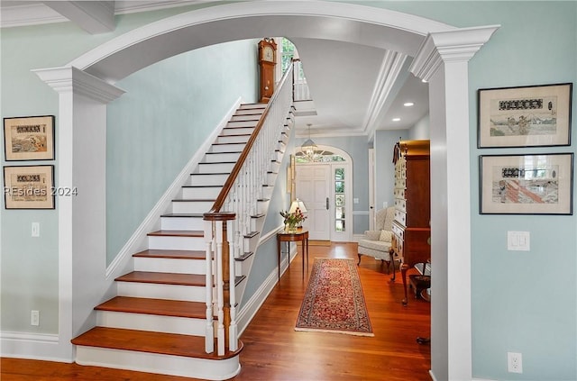 stairs featuring hardwood / wood-style floors, crown molding, and ornate columns