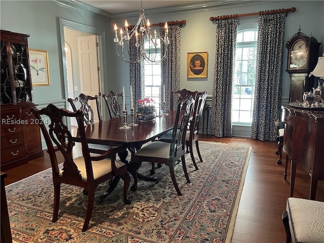 dining area with a notable chandelier, dark wood-type flooring, a wealth of natural light, and ornamental molding