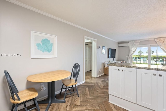 kitchen with a wall unit AC, white cabinets, ornamental molding, dark parquet flooring, and a textured ceiling