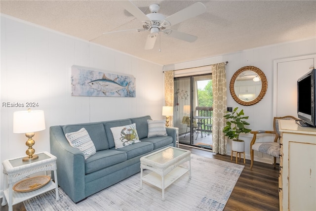 living room featuring hardwood / wood-style flooring, ceiling fan, and a textured ceiling