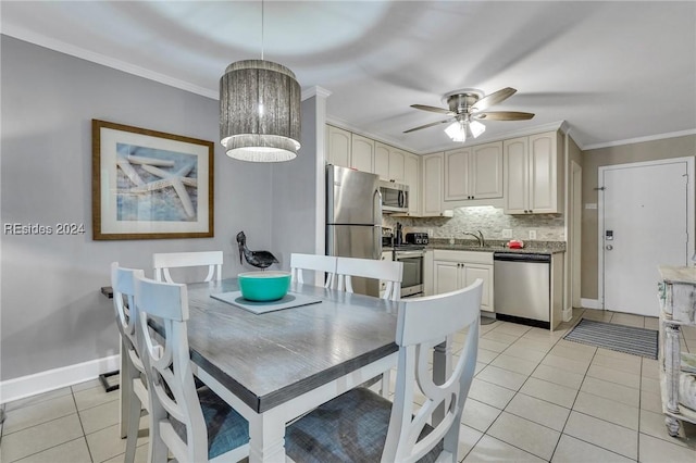 tiled dining room with sink, crown molding, and ceiling fan