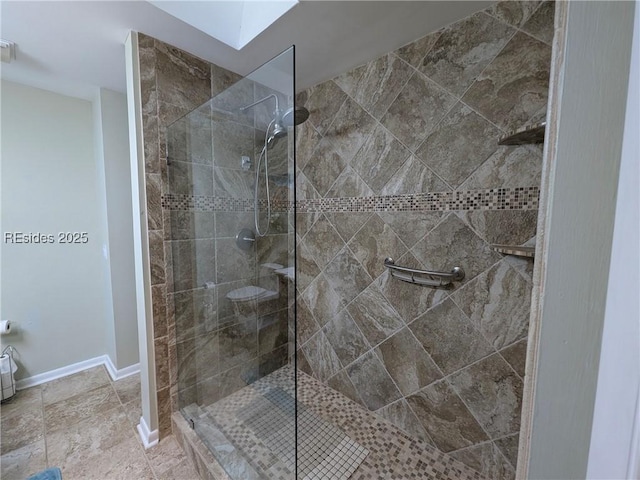 bathroom with a tile shower and a skylight