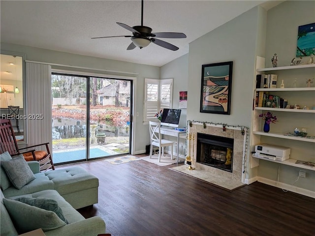 living room featuring a tile fireplace, wood-type flooring, lofted ceiling, and ceiling fan