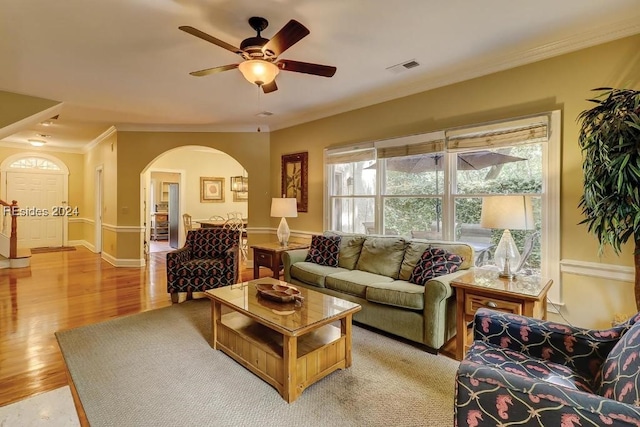 living room featuring ornamental molding, light hardwood / wood-style floors, and ceiling fan