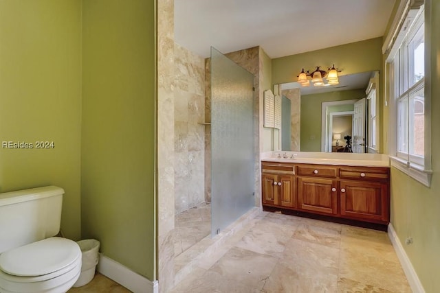 bathroom with vanity, tiled shower, a healthy amount of sunlight, and toilet