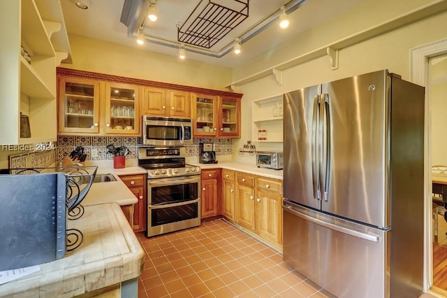 kitchen featuring light tile patterned floors, decorative backsplash, track lighting, and appliances with stainless steel finishes