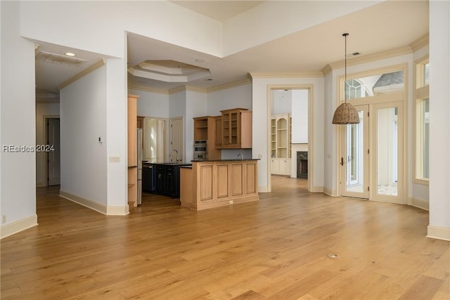 kitchen with pendant lighting, sink, ornamental molding, a tray ceiling, and light hardwood / wood-style flooring