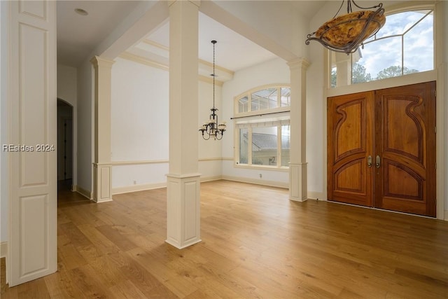 entrance foyer with ornate columns, a chandelier, and light hardwood / wood-style floors