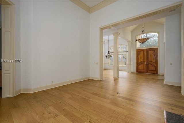 foyer featuring decorative columns, crown molding, and light hardwood / wood-style flooring