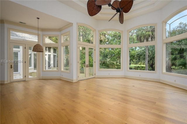 unfurnished sunroom featuring a raised ceiling and ceiling fan