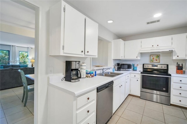 kitchen with stainless steel appliances, light tile patterned flooring, sink, and white cabinets