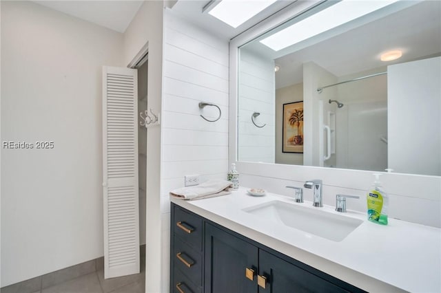 bathroom with vanity, a skylight, tile patterned flooring, and a shower