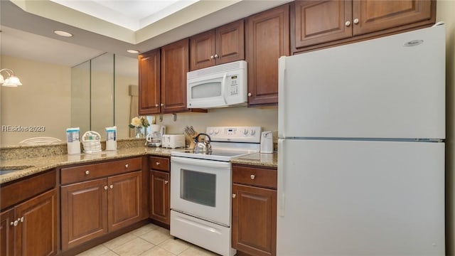 kitchen with light tile patterned flooring, light stone countertops, and white appliances