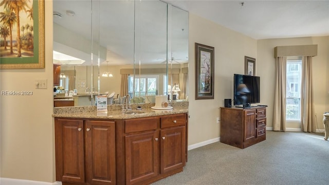 kitchen with sink, hanging light fixtures, light carpet, a healthy amount of sunlight, and light stone countertops