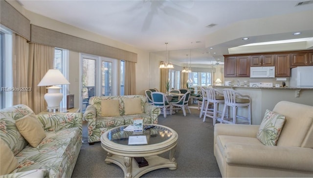 carpeted living room with a notable chandelier