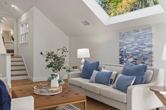 living room featuring wood-type flooring and vaulted ceiling with skylight