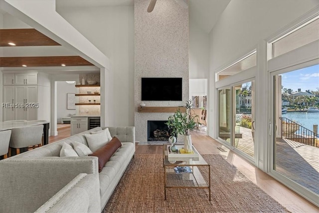 living room featuring a towering ceiling, wood-type flooring, and a fireplace