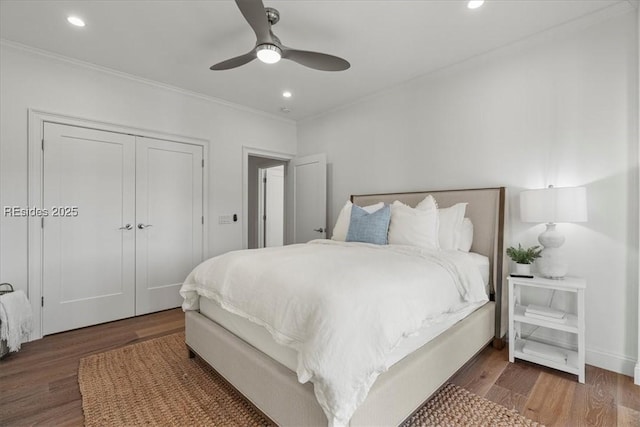 bedroom with ornamental molding, dark hardwood / wood-style floors, ceiling fan, and a closet