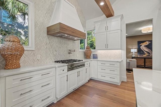 kitchen with white cabinetry, light hardwood / wood-style floors, stainless steel gas cooktop, and custom range hood