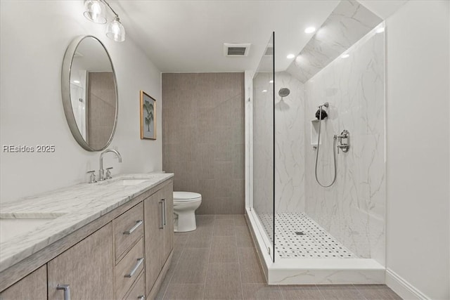 bathroom with vanity, tiled shower, tile patterned floors, and toilet