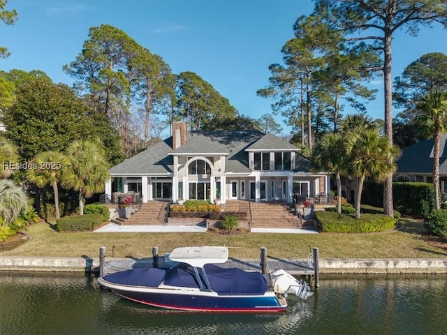 rear view of house with a yard and a water view