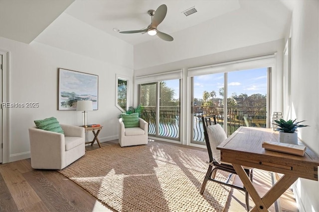 sunroom / solarium with plenty of natural light, a raised ceiling, and ceiling fan