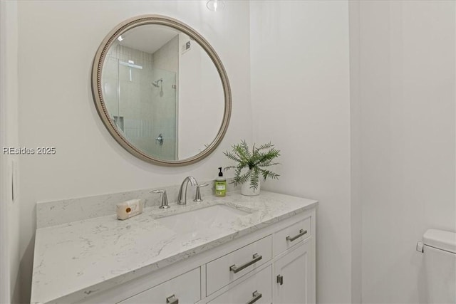 bathroom featuring vanity, a tile shower, and toilet