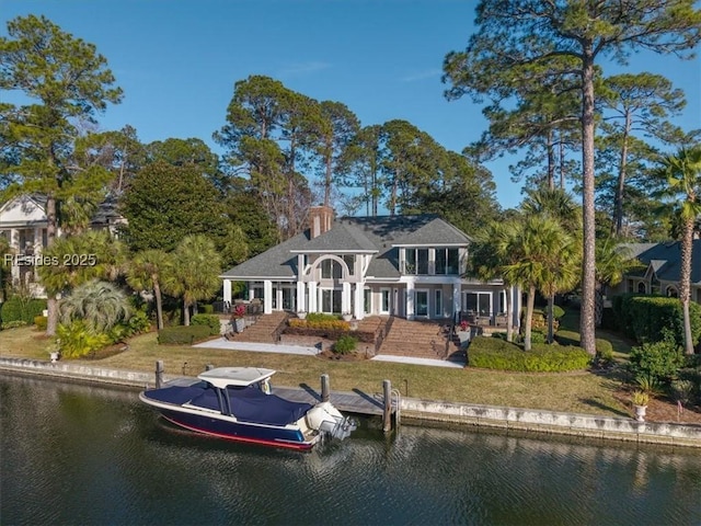 back of property with a water view and a yard