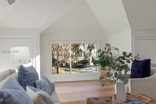 living room with vaulted ceiling, a healthy amount of sunlight, and hardwood / wood-style floors