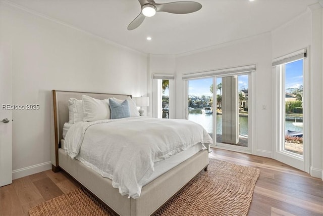 bedroom with access to exterior, light wood-type flooring, ceiling fan, and a water view