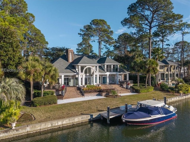 rear view of house with a water view and a yard