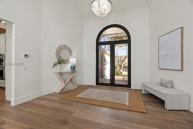 entrance foyer featuring dark hardwood / wood-style flooring, crown molding, french doors, and a chandelier